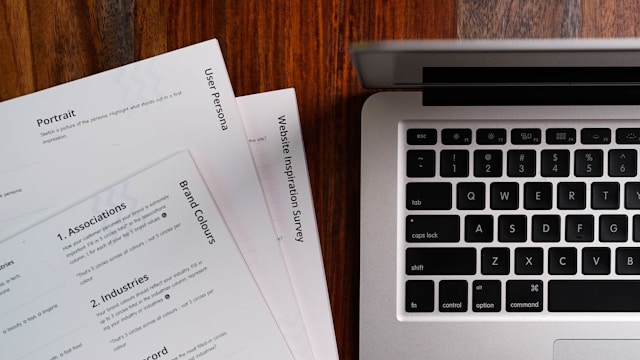 Documentos impressos ao lado de um computador portátil