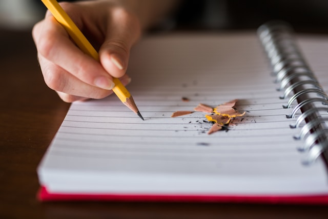 Lápis a escrever num caderno de argolas